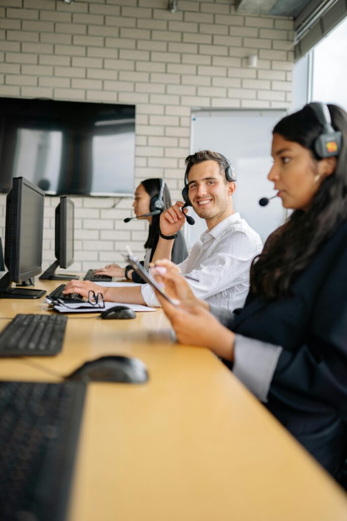 Three professionals at a call center collaborating in a modern office environment.